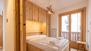 Une chambre à coucher en bois, avec un lit, une petite table et un balcon doté d’une balustrade.