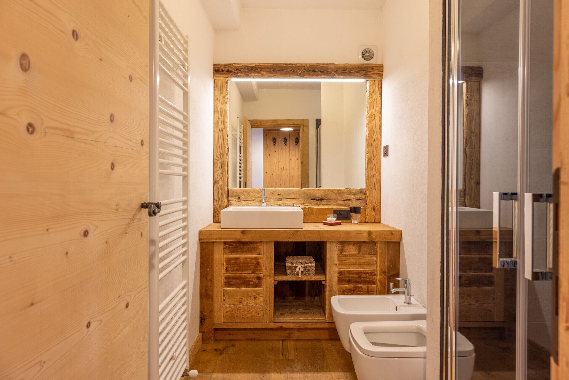 Un baño con tocador de madera, un espejo grande, un lavabo, un bidé y una zona de ducha.