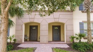 Un edificio con dos puertas simétricas, un acceso empedrado y una pequeña zona de estar.