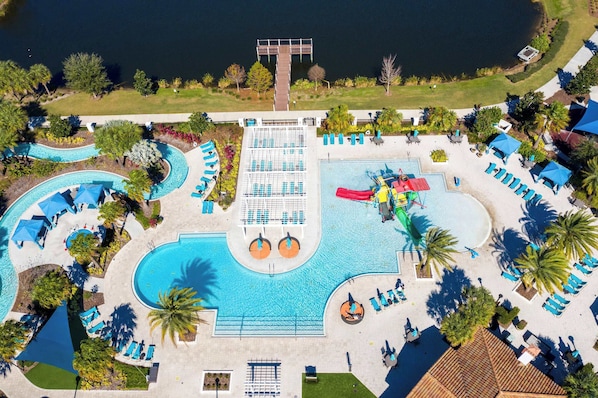 Vista aérea de un resort con una gran piscina, varias zonas de descanso y un muelle que da a una masa de agua.