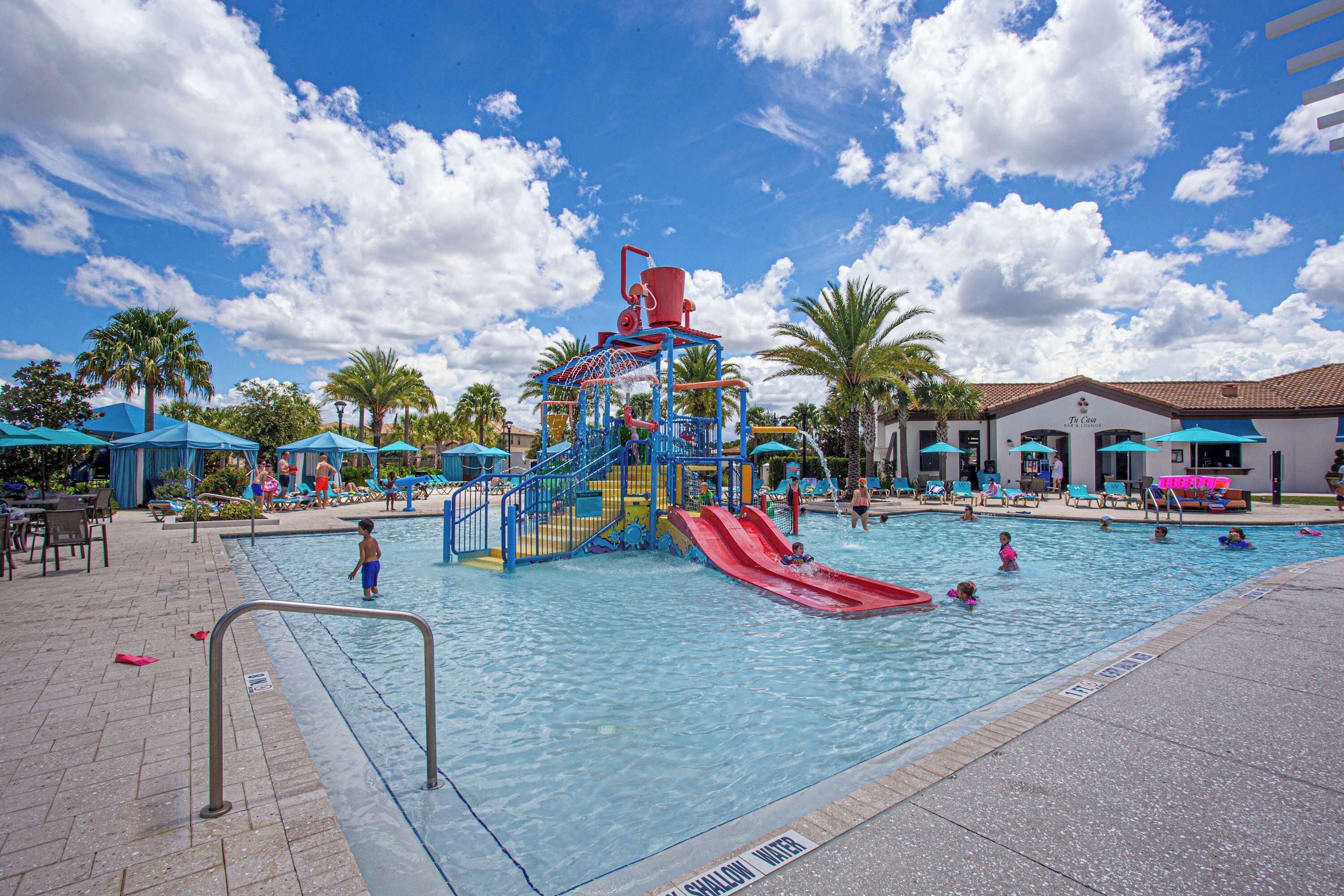 A swimming pool with a water slide and a children's play area.