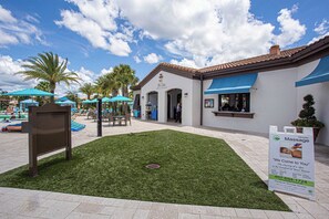 Un patio con una zona de bar/lounge, palmeras y un cartel anunciando servicios de masaje.