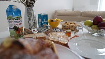 Una mesa de comedor con comida, un florero con flores y un sofá al fondo.