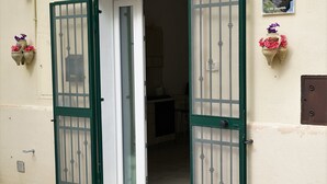 A building entrance with a green metal gate, a door with a glass panel, and a number '104' on the wall.