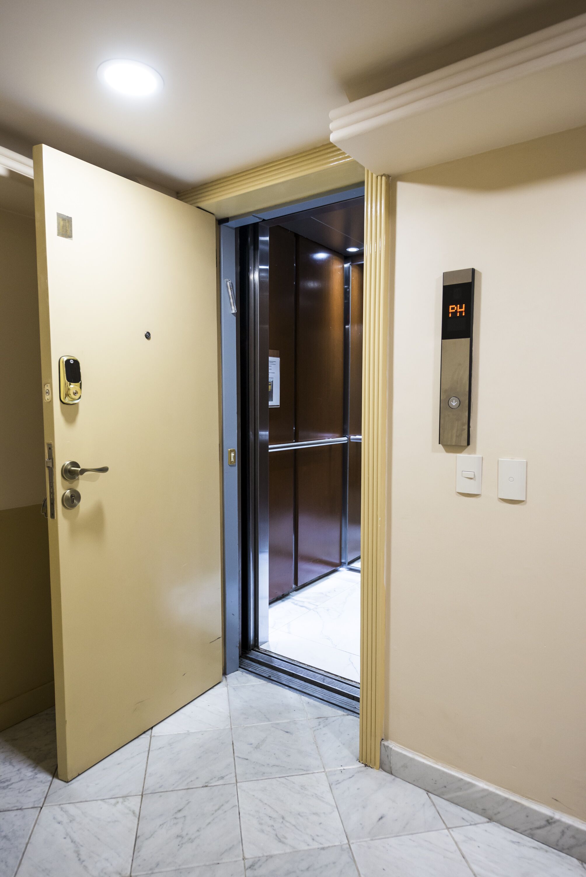An elevator with a PH button, a door with a keypad lock, and a tiled floor.