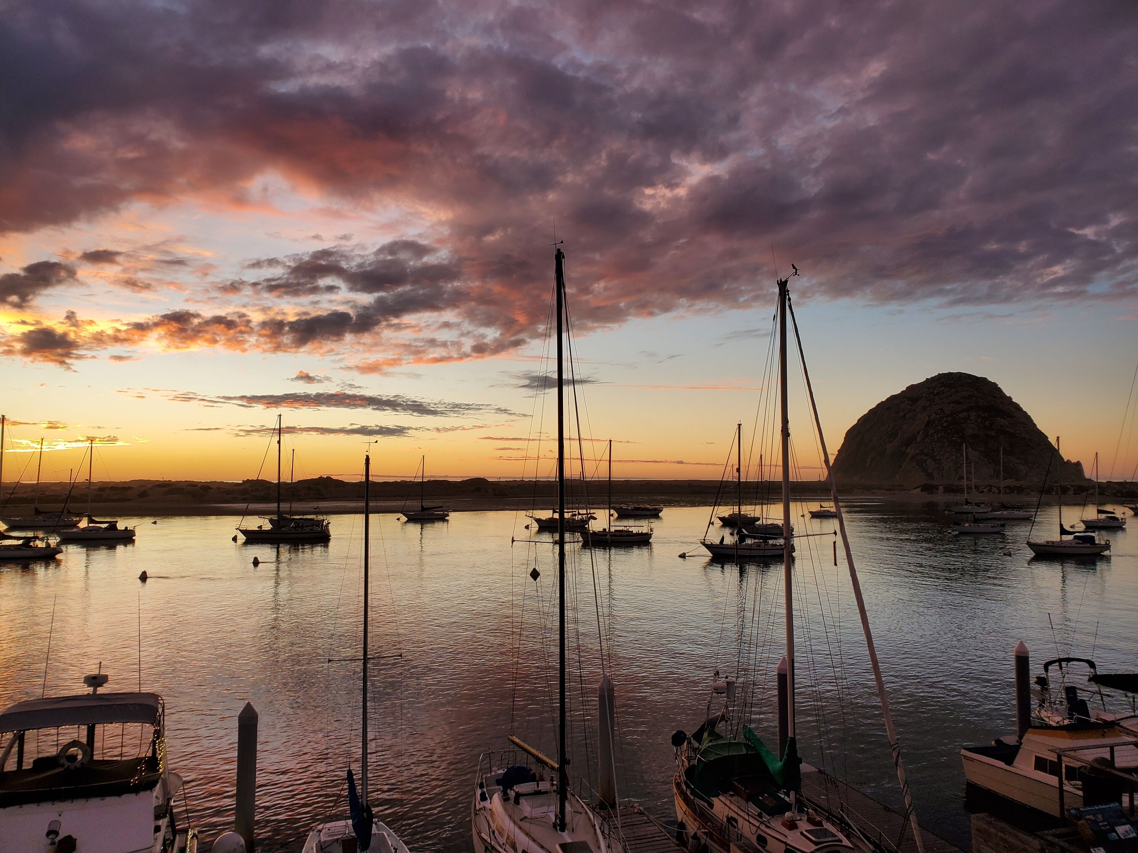 A marina with multiple boats docked at sunset.