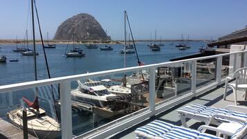 Un balcón con sillones blancos y vistas a barcos amarrados en un puerto deportivo.