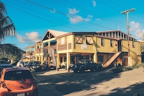 Um edifício amarelo com varanda e escadaria que leva à entrada.