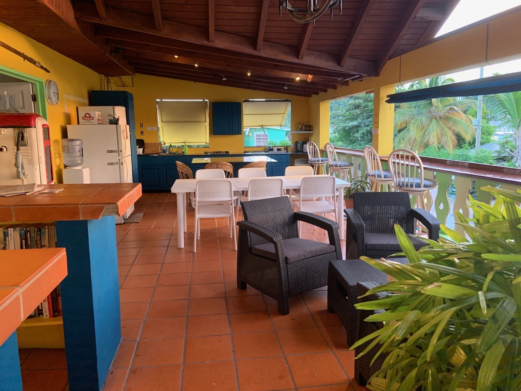 Un restaurante con mesas al aire libre, zona de cocina y vistas al entorno verde.