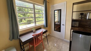 A compact kitchen with a window, a small table, a chair, and a refrigerator. - The Waterfront Inn - Hostel (English Harbour)