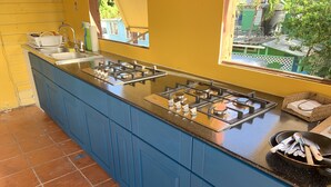 A kitchen with a gas stove, sink, and blue cabinets. - The Waterfront Inn - Hostel (English Harbour)