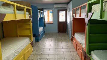 Habitación tipo dormitorio con literas, piso de baldosas y una puerta que da a otra habitación.