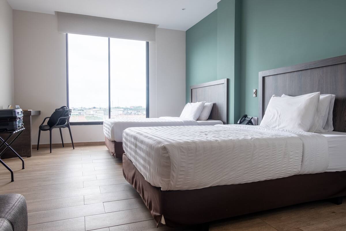 A hotel room with two beds, a desk, and a chair.