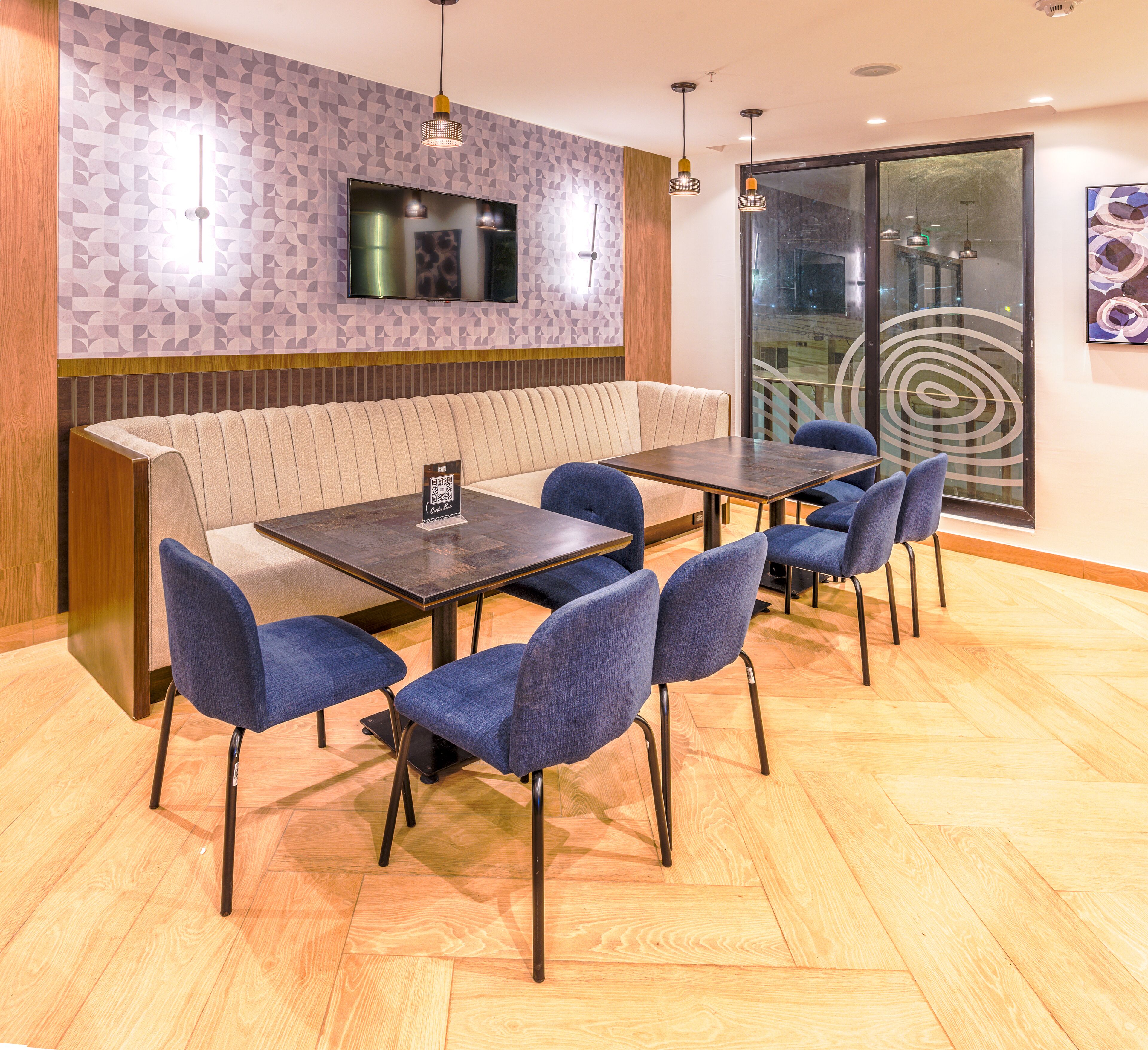 Un espace repas comprenant des banquettes, une table avec des chaises, un téléviseur fixé au mur et une grande fenêtre offrant une vue panoramique.