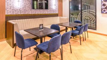Un espace repas comprenant des banquettes, une table avec des chaises, un téléviseur fixé au mur et une grande fenêtre offrant une vue panoramique.