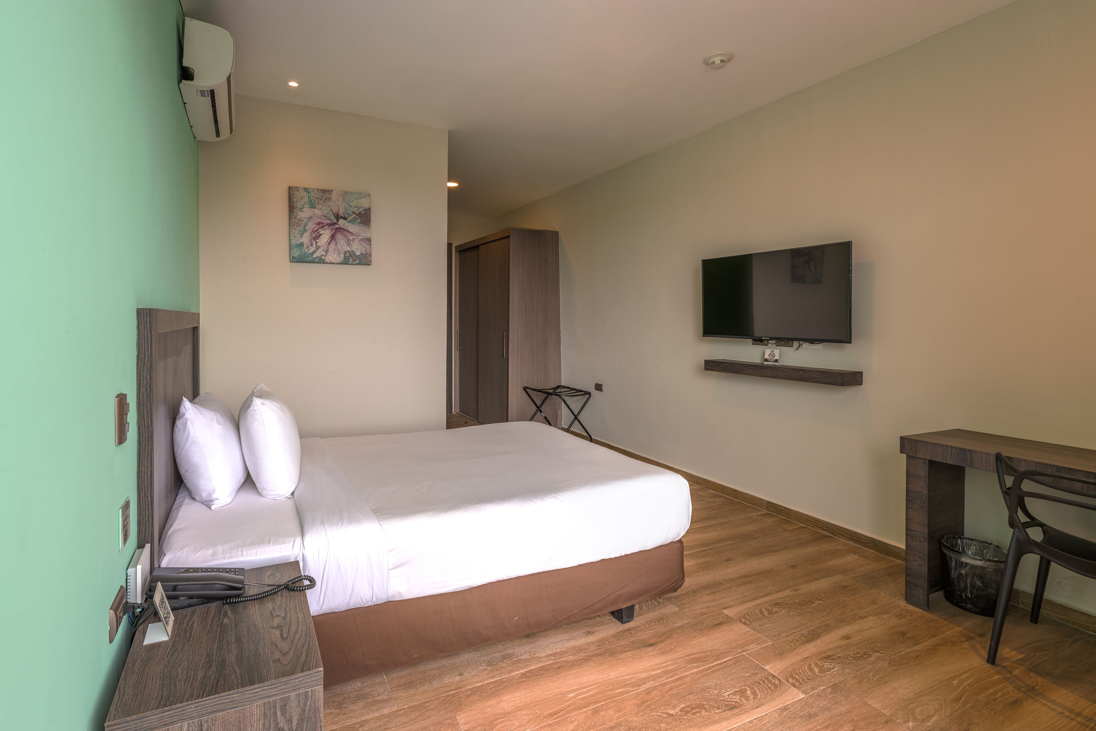 Camera d'albergo moderna con un letto grande, una scrivania, un televisore e un quadro appeso al muro.