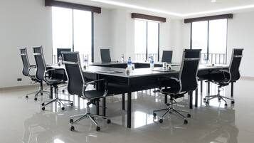 A conference room with a long table, black chairs, and large windows.