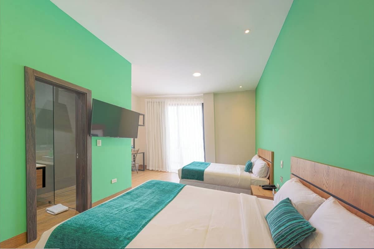 A hotel room with two beds, a TV, and a window with curtains.