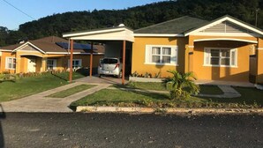 Ein zweistöckiges Haus mit überdachter Auffahrt und einem geparkten Auto.