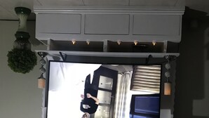Ein Zimmer mit einem großen Spiegel, der ein Bett, ein Fenster mit Vorhängen und eine Topfpflanze reflektiert.