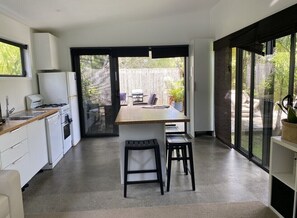A modern kitchen with a central island, bar stools, and a view of the outdoor patio area.