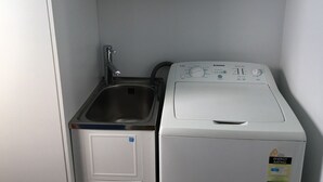 A compact laundry area with a washing machine and a sink. - Bali in Berrara (Berrara)