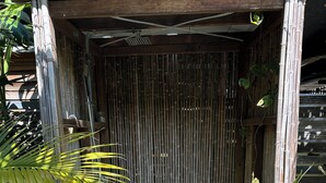 A wooden structure with a bamboo wall, a ceiling fan, and a potted plant. - Bali in Berrara (Berrara)