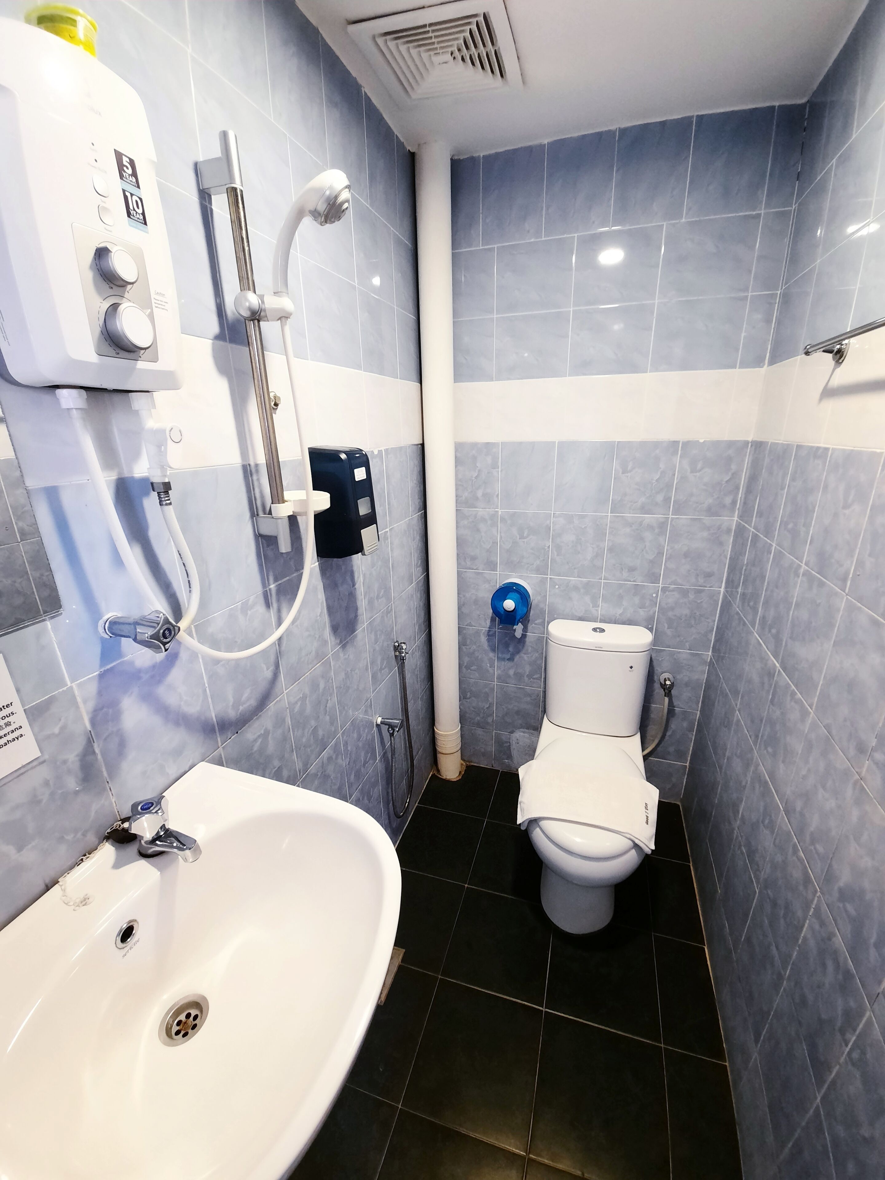 A bathroom with a white sink, a toilet, and a shower unit with a handheld showerhead.