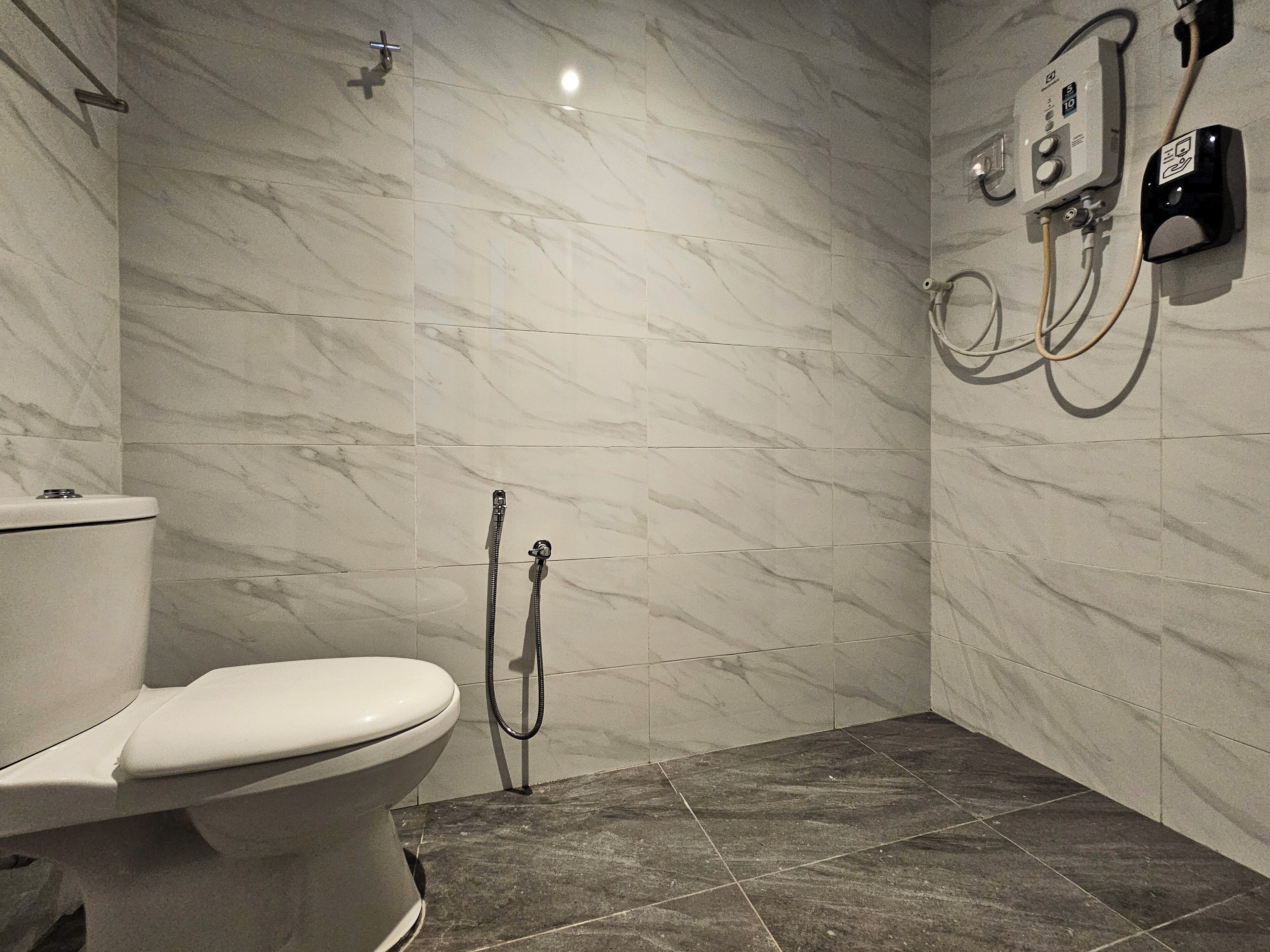 A bathroom with a toilet, a shower, and a wall-mounted control panel.
