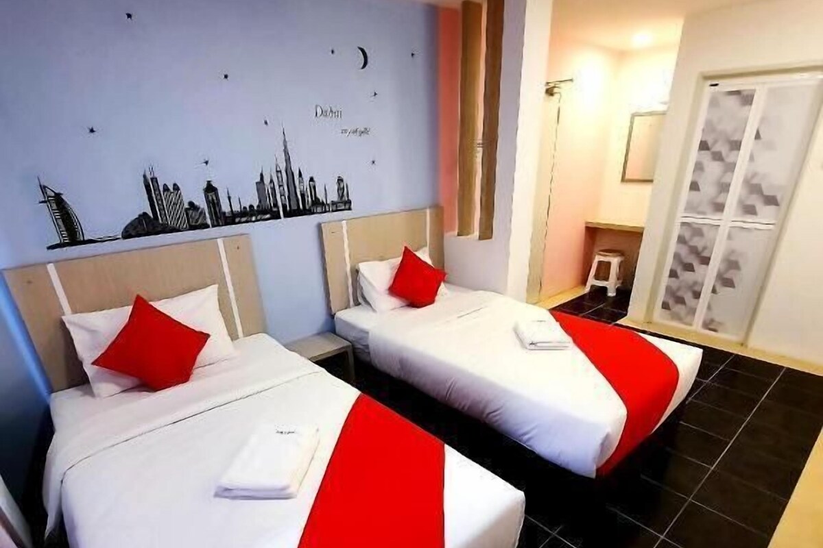A hotel room with two beds, a cityscape wall art, a small stool, and a wardrobe.