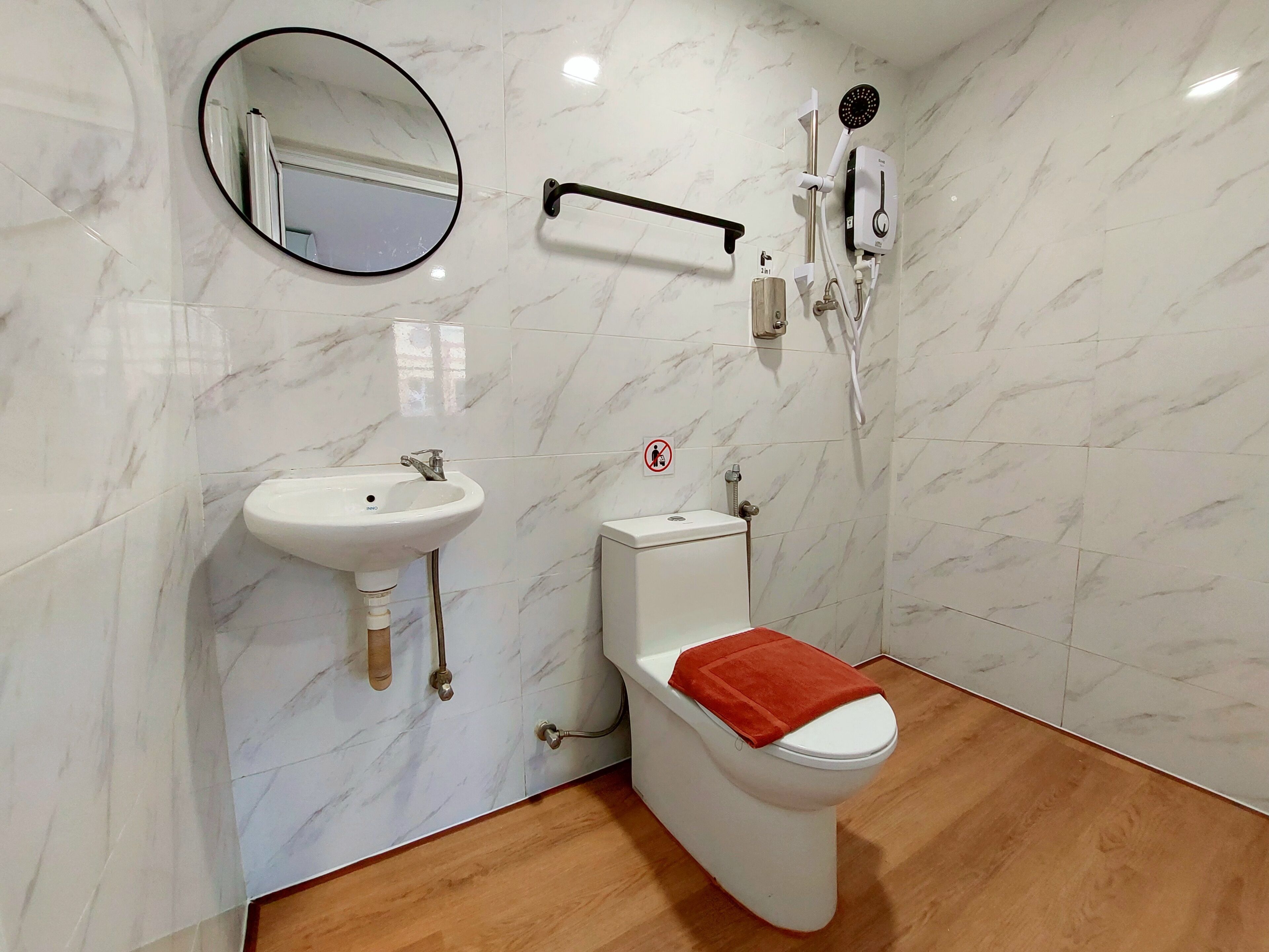 Et badeværelse med toilet, håndvask, spejl og brusebad.