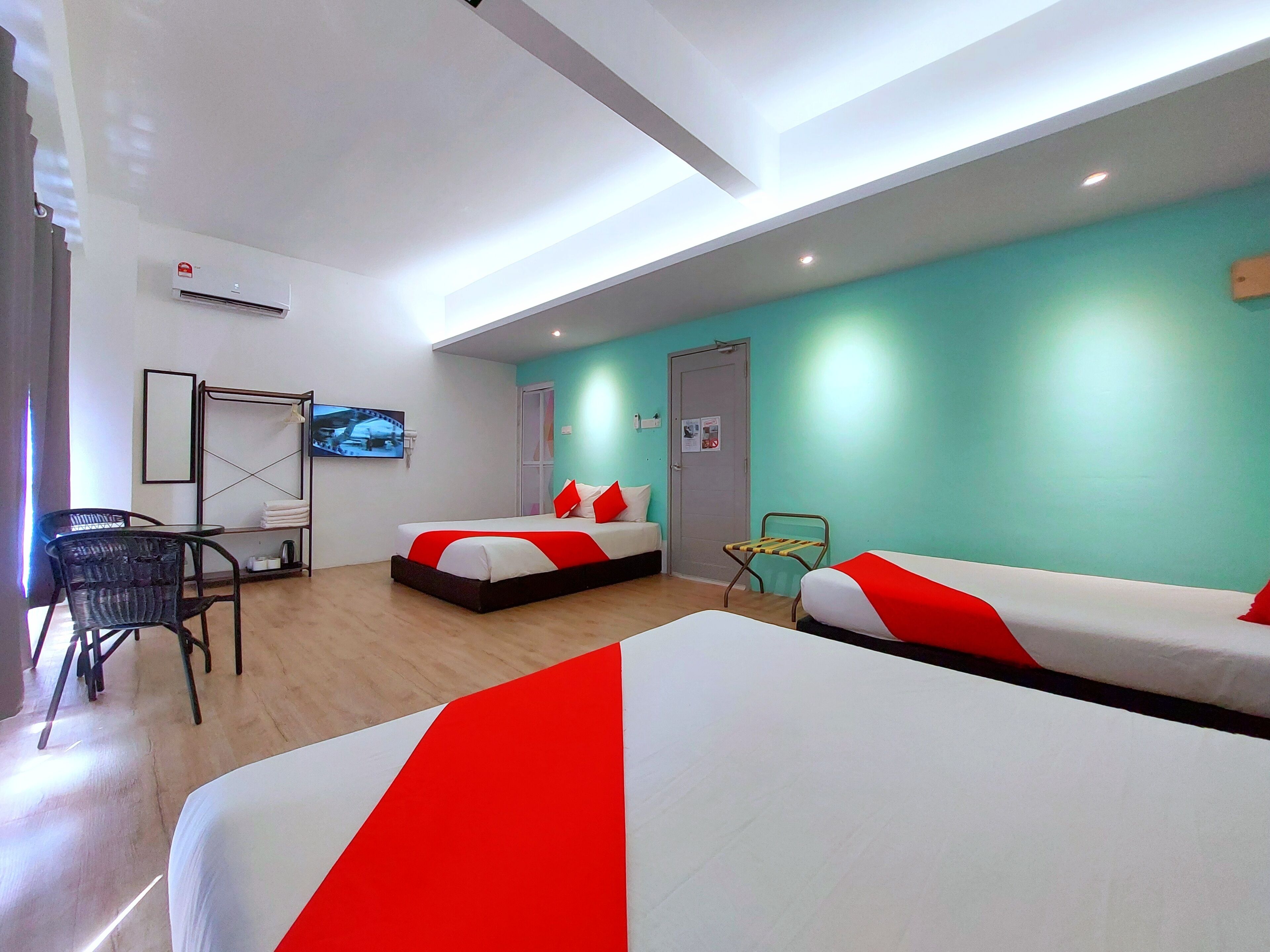 Una habitación de hotel con dos camas, televisión, una silla y un armario.