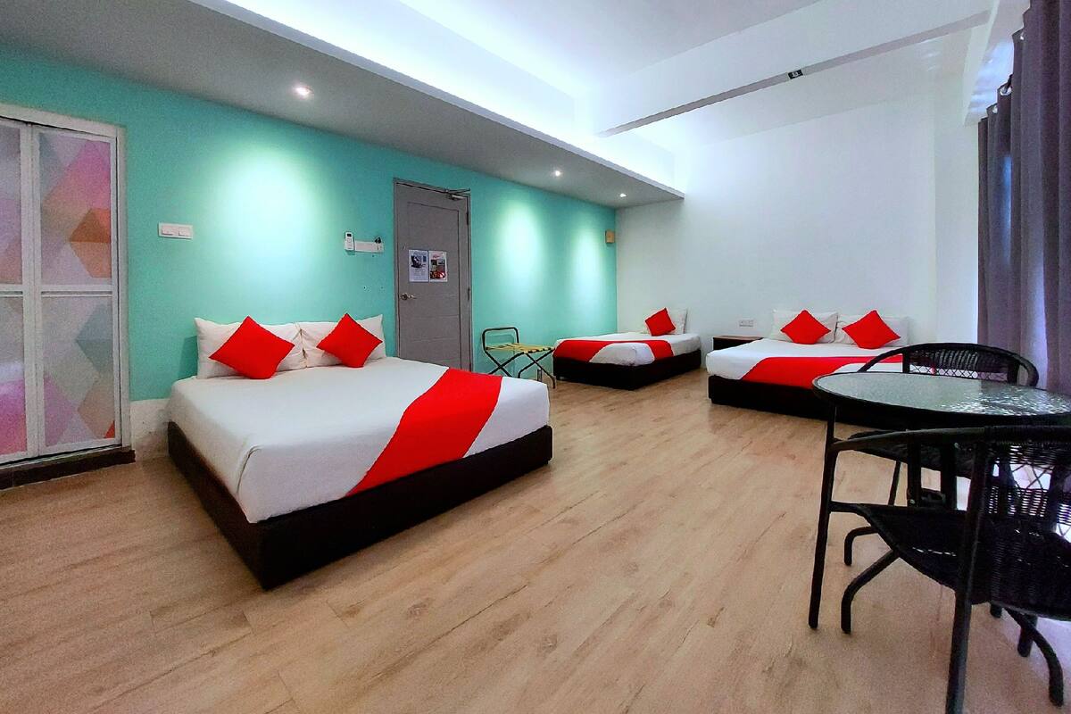 A hotel room with two beds, a small table, and a chair.