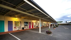 A motel with individual rooms, a covered parking area, and outdoor seating. - Lamington Hotel Motel (Maryborough)
