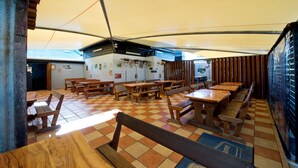A restaurant with wooden tables and benches, a tiled floor, and a high ceiling. - Lamington Hotel Motel (Maryborough)