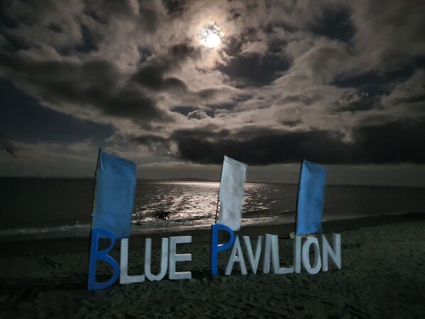A beach scene with the text "BLUE PAVILION" on the sand.