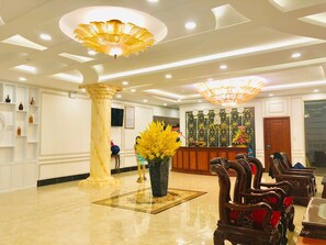 A hotel lobby with marble flooring, a reception desk, and a chandelier. - Khach san Sao Nam (My Tra)