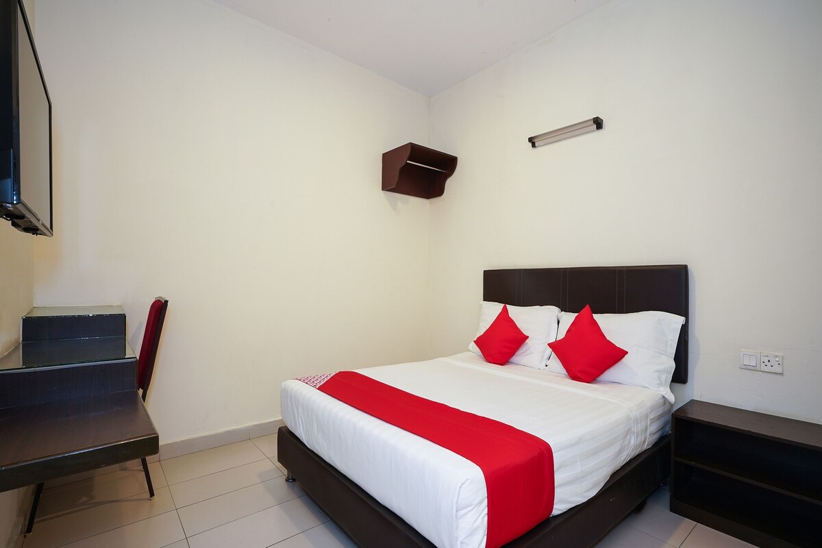 A neatly arranged hotel room with a bed, bedside tables, a desk, and a TV.