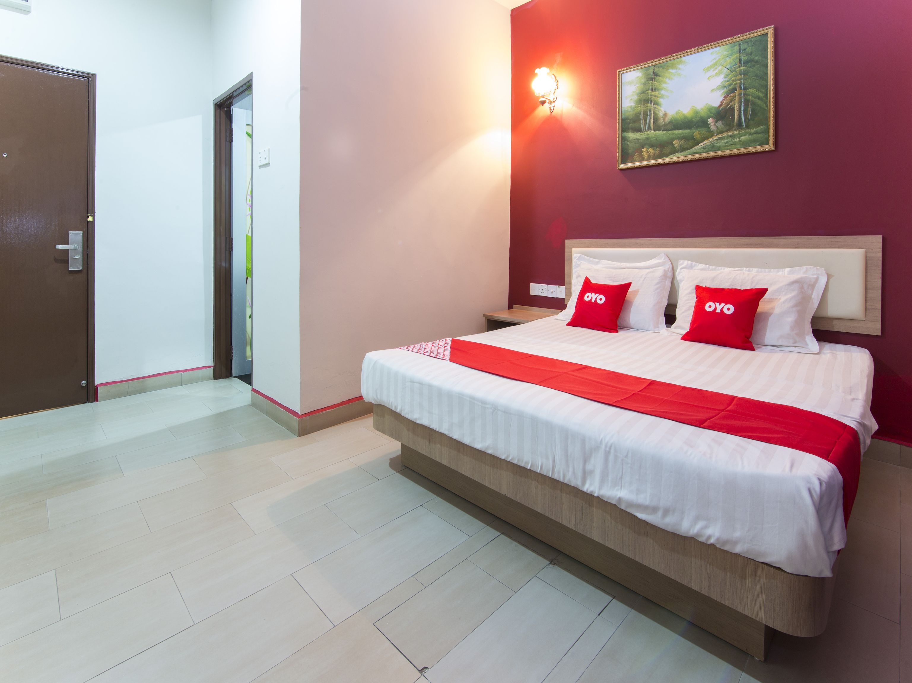 Habitación de hotel impecable con una cama grande, una mesita de noche, una lámpara de pared y un cuadro.