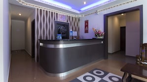 A hotel reception area with a curved reception desk, a wall-mounted TV, and a floral arrangement. - Valley View Hotel (Lumut)