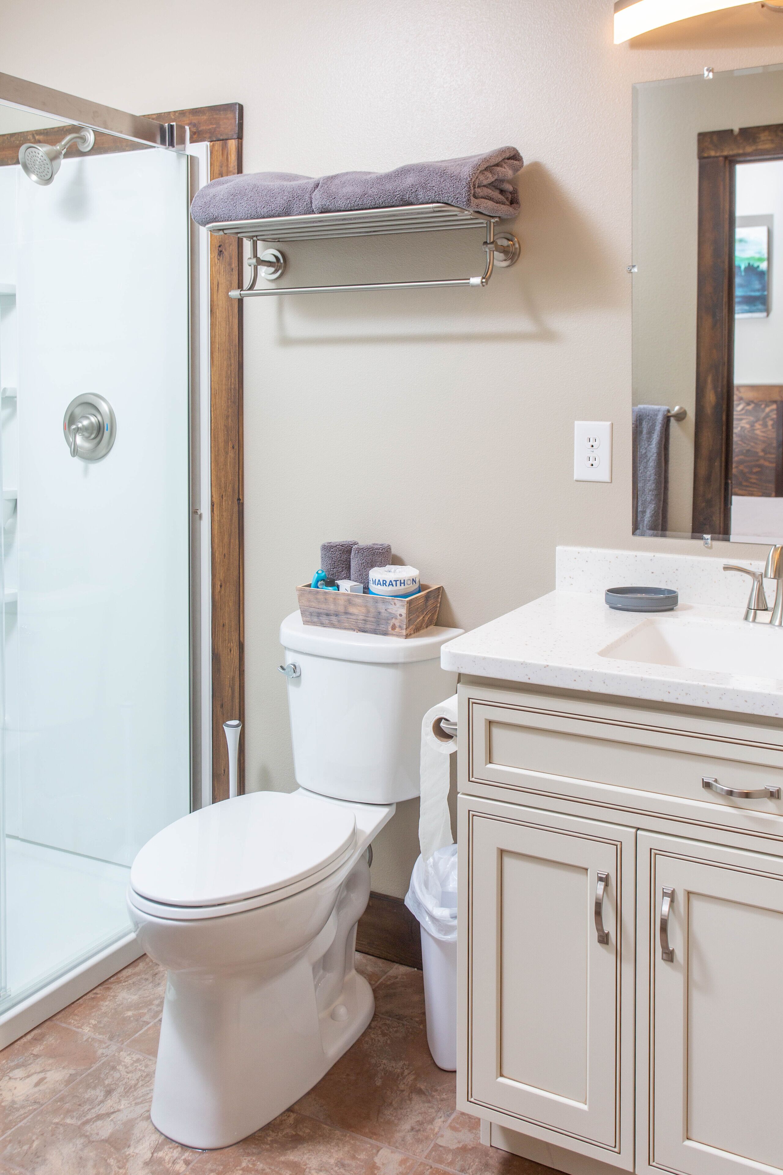 A bathroom with a toilet, a shower, a sink, and a mirror.