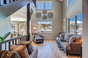 Relax in a spacious room with a comfortable seating area, dining table, and large window offering a mountain view.