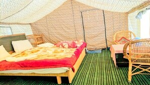 A tent-style room with a bed, wicker chairs, and a small table. - Apple Cottage Nubra - Glamping (Leh)