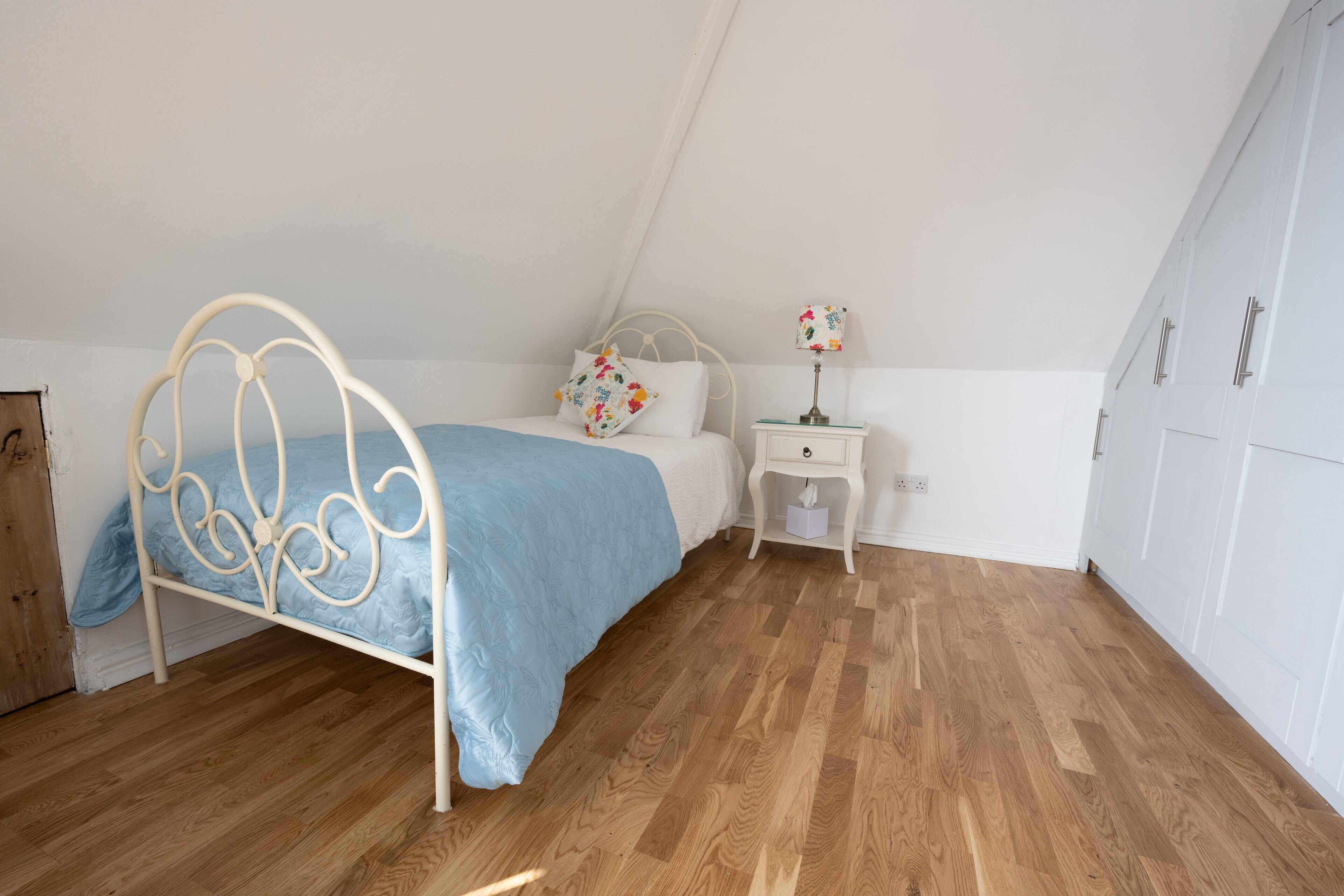 Een slaapkamer met een bed, nachtkastje, lamp en kledingkast.
