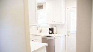 A kitchen with white cabinetry, a dishwasher, and a coffee maker.