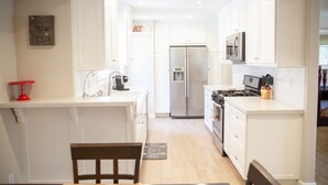 A modern kitchen with white cabinetry, stainless steel appliances, and a red accent on the countertop.