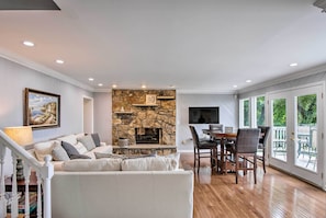 Cozy living room with a stone fireplace, sofa, and dining area.