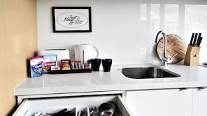 A kitchen with a coffee maker, mugs, and a framed sign on the wall. - Short Stay Apartment at Flinders (Melbourne)
