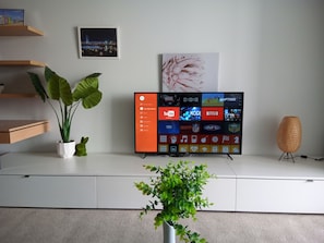 Enjoy a contemporary living space with a flat-screen TV, a shelf with a framed picture, and a potted plant.