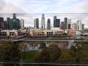 A cityscape with modern buildings, a river, and a bridge. - Short Stay Apartment at Flinders (Melbourne)